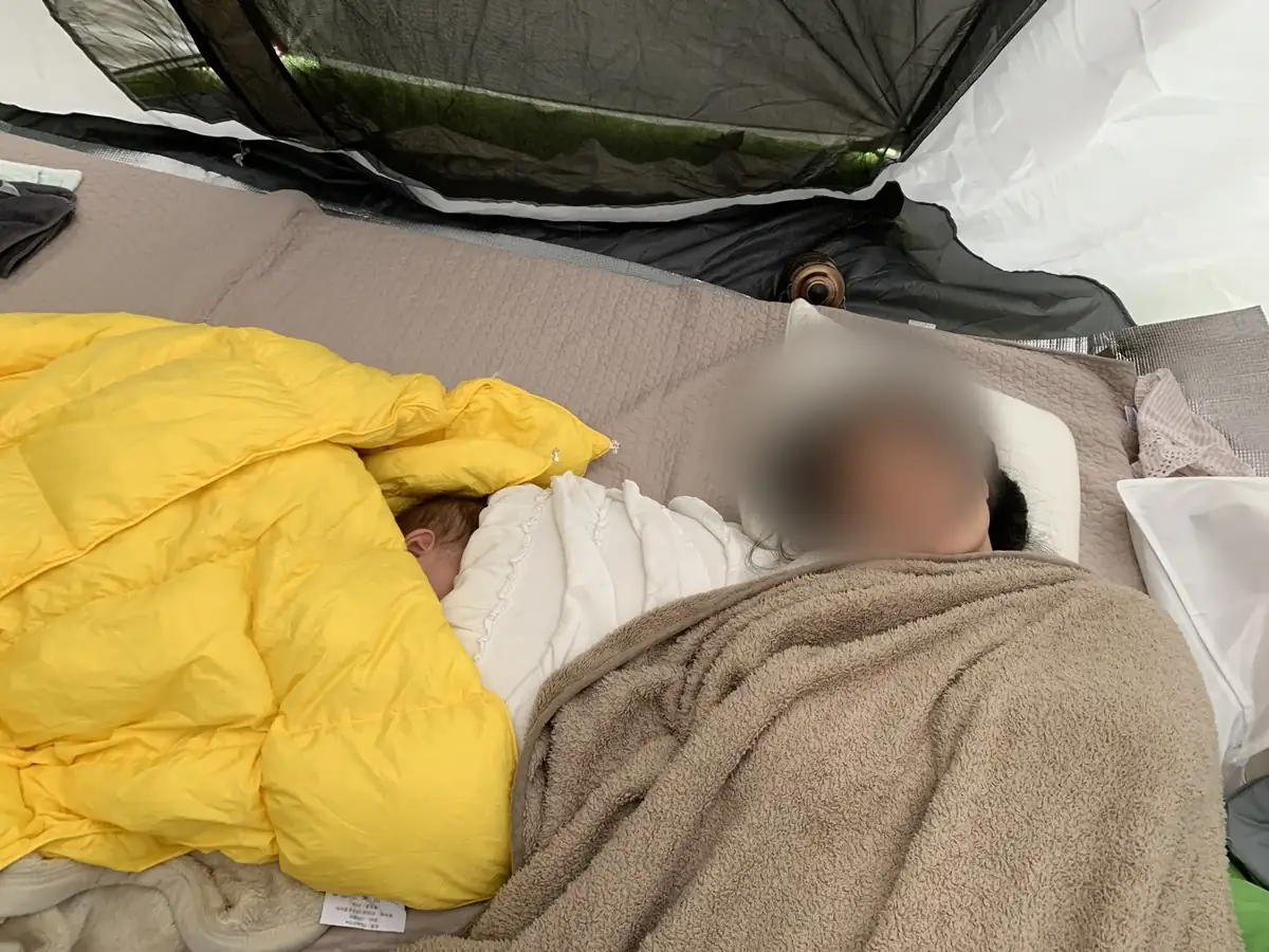 0歳の次女とテント内の寝具で休んでいる様子
