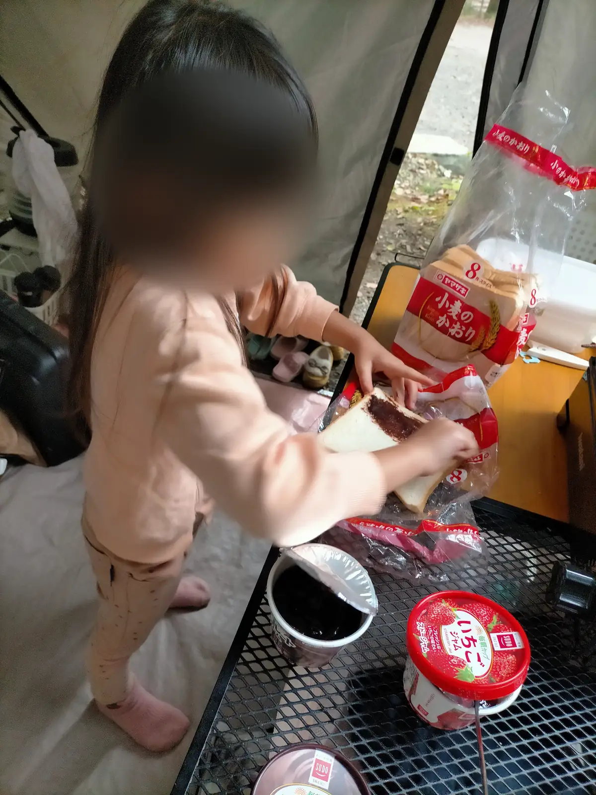 道志の森キャンプ場の3日目の朝、長袖と長ズボンでジャムサンドを作る子ども